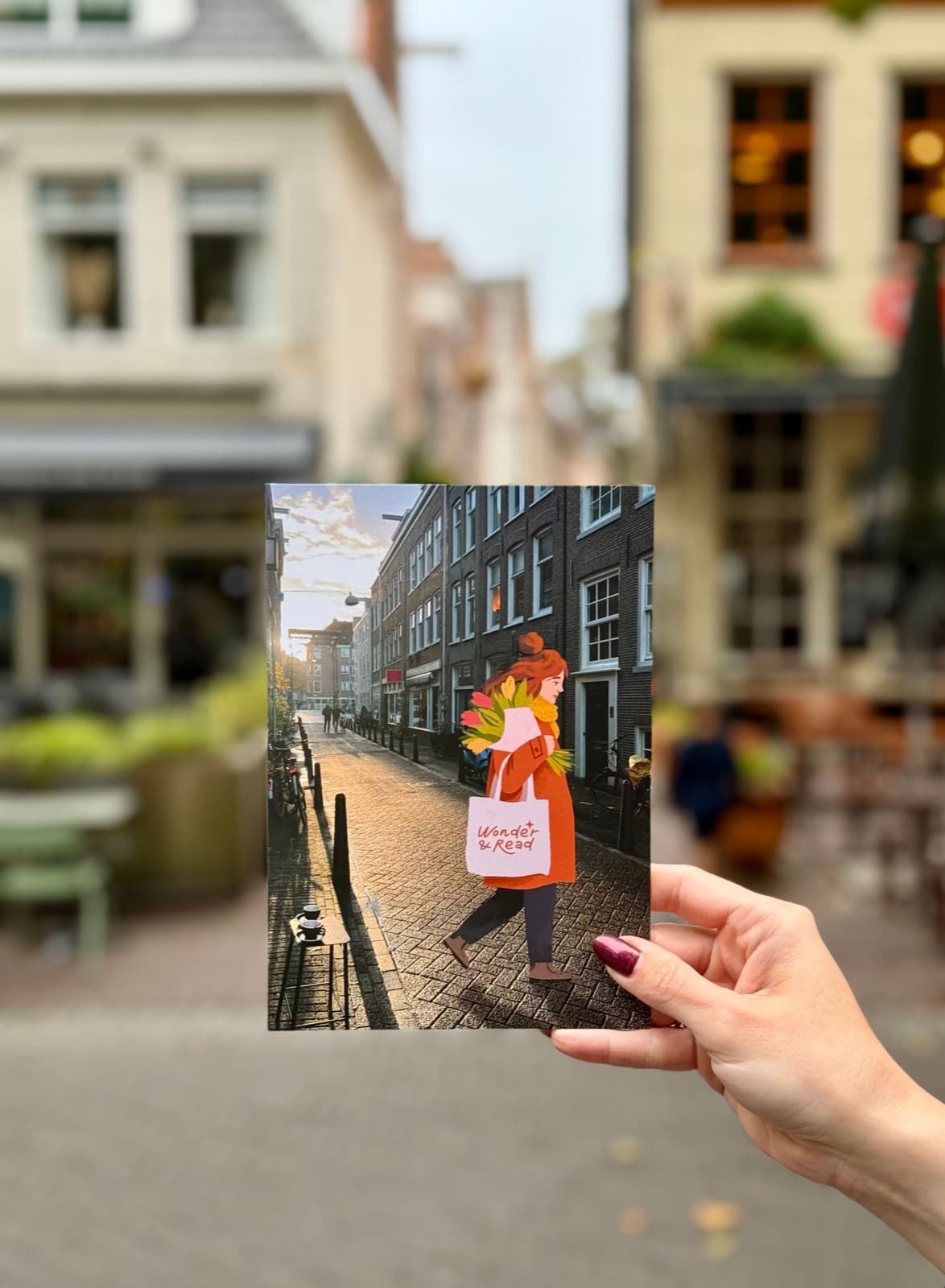 The Amsterdam street print — a girl with flowers and a Wonder & Read tote — held up in an Amsterdam street